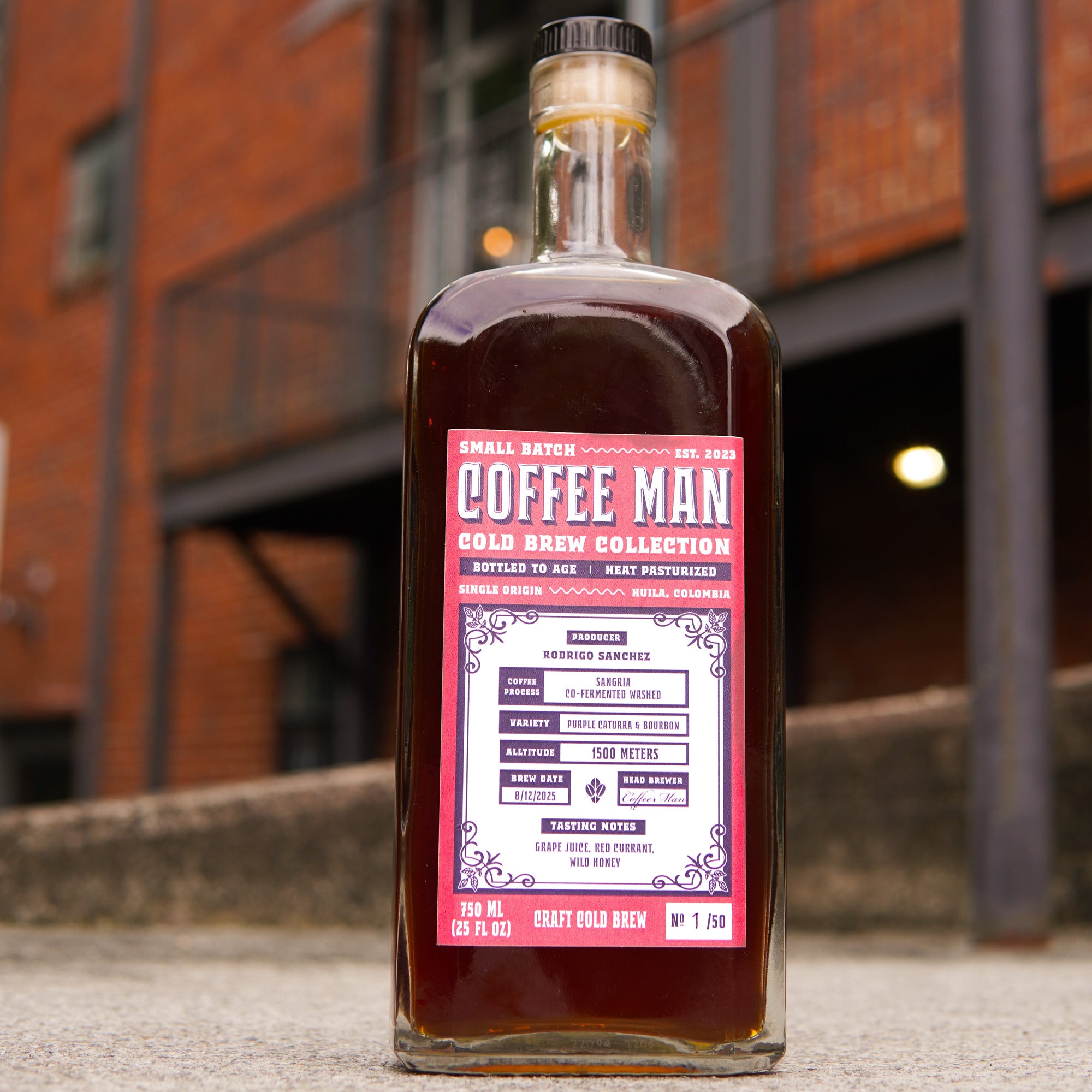 Bottle of Coffee Man coffee brew collection with a pink label against a cafe background.