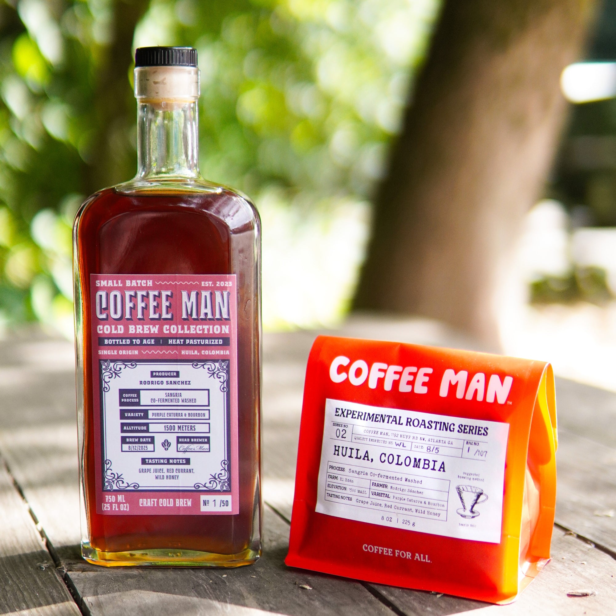 Bottle and bag of Coffee Man Sangria coffee on a wooden surface with greenery in the background
