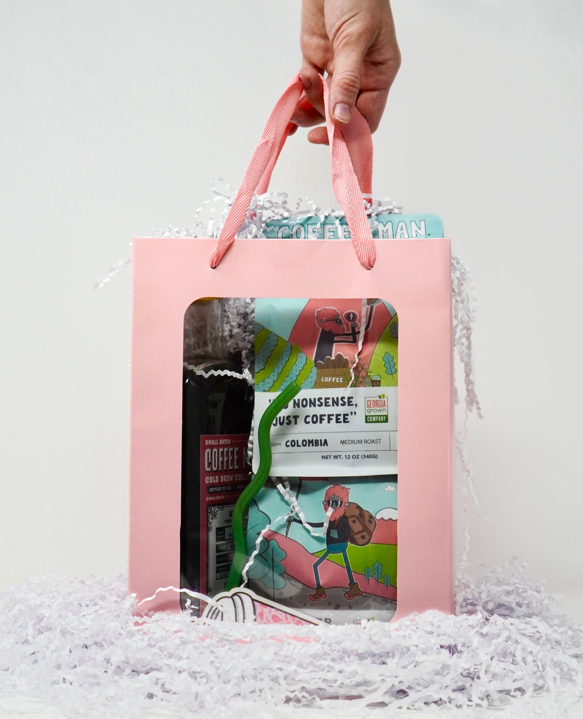 Pink gift bag with cartoon design held by a hand against a white background