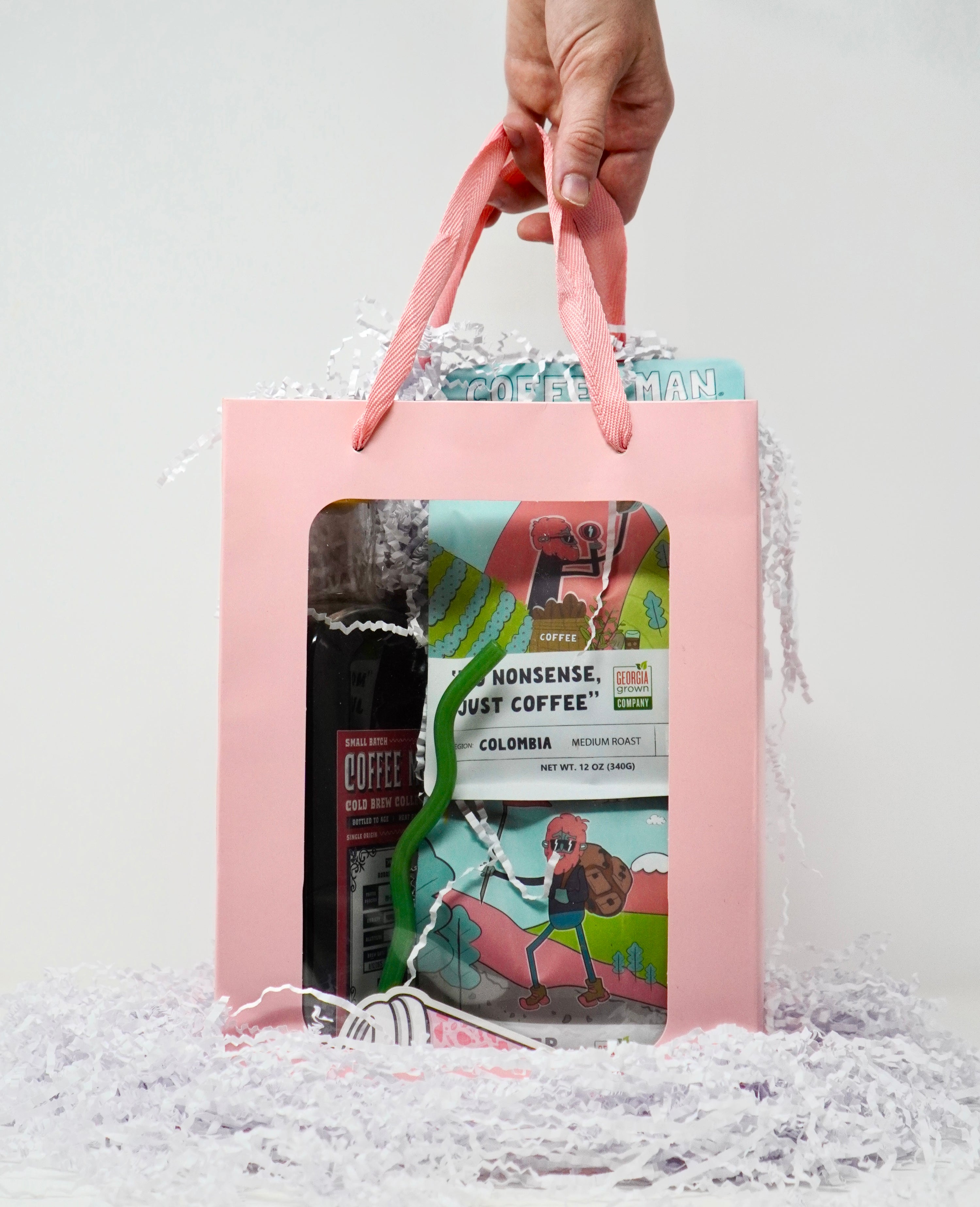 Pink gift bag with cartoon design held by a hand against a white background